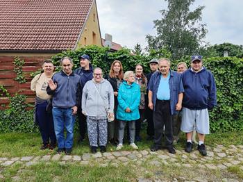Gospodarze oraz uczestnicy stojący na tle żywopłotu